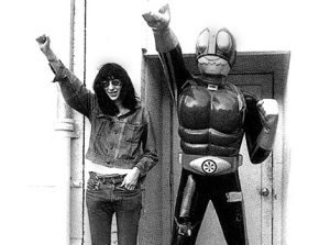 Joey Ramone raises a fist with .. a robot. 